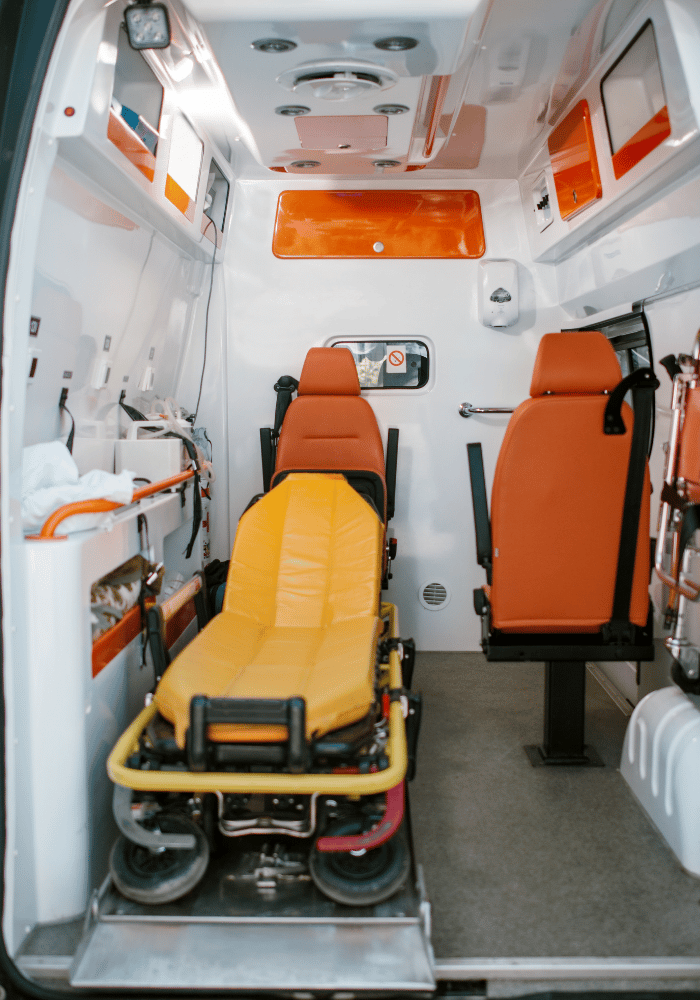 Interior of a medical vehicle featuring a yellow patient gurney and orange seating for secure stretcher transport.
